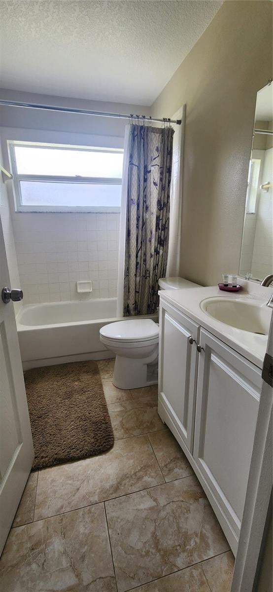 full bathroom with a textured ceiling, vanity, toilet, and shower / bath combination with curtain