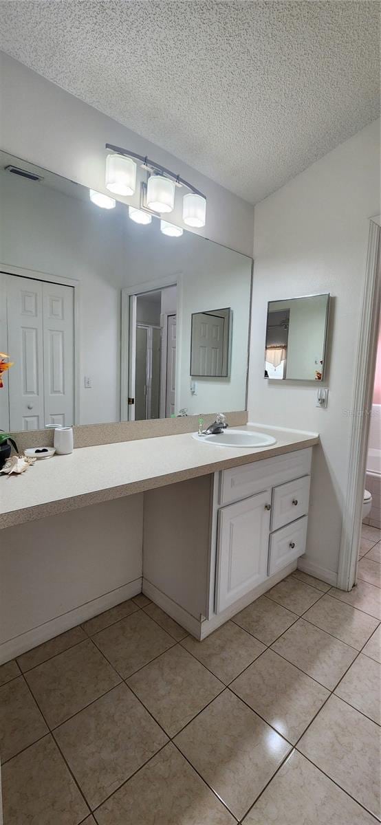 bathroom featuring a textured ceiling, vanity, an enclosed shower, tile patterned flooring, and toilet