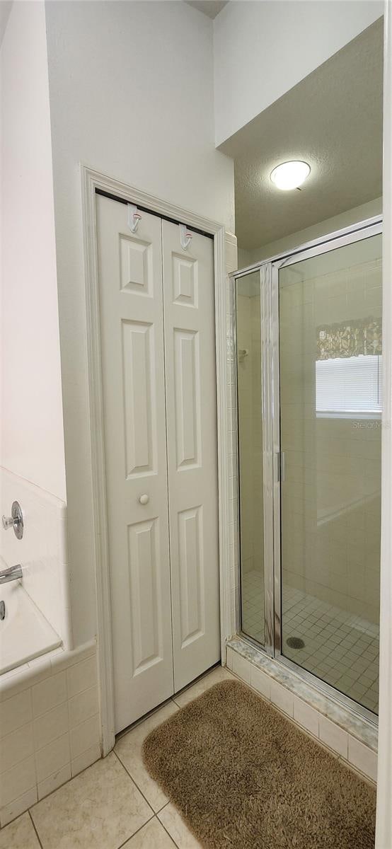 bathroom with separate shower and tub and tile patterned flooring