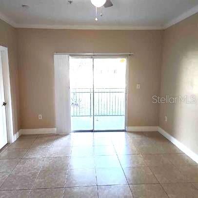 tiled spare room featuring crown molding and ceiling fan