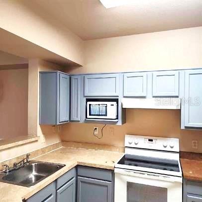 3701 Castle Pines Ln Unit 3914, Orlando, FL 32839 - kitchen with white appliances, light countertops, gray cabinetry, a sink, and ventilation hood