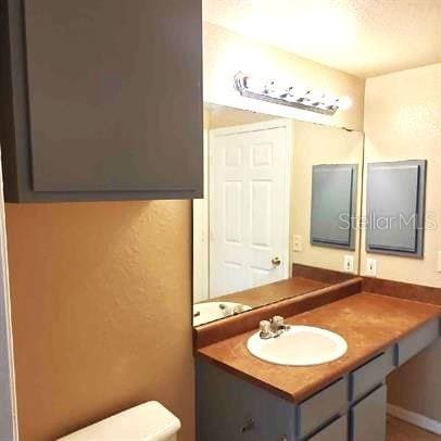 3701 Castle Pines Ln Unit 3914, Orlando, FL 32839 - half bathroom with a textured wall, vanity, and toilet