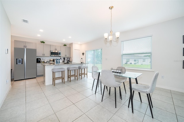 tiled dining area featuring a notable chandelier and sink