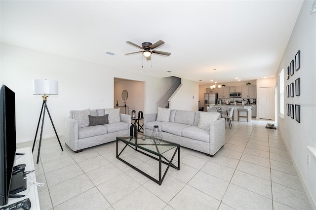 tiled living room featuring ceiling fan with notable chandelier