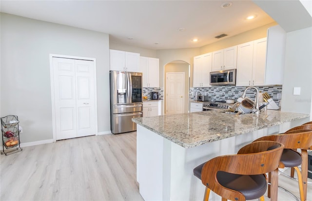 kitchen featuring light stone countertops, stainless steel appliances, backsplash, and kitchen peninsula