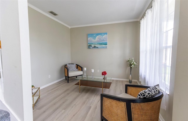 living area with ornamental molding and light hardwood / wood-style floors