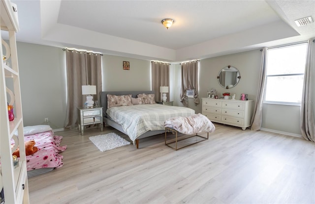 bedroom featuring light hardwood / wood-style floors and a raised ceiling