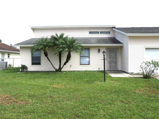 rear view of house with central AC, a lawn, and a garage