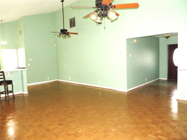 empty room featuring high vaulted ceiling, dark parquet flooring, and ceiling fan