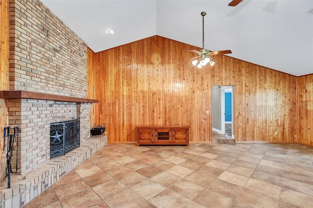 unfurnished living room with high vaulted ceiling, a brick fireplace, wood walls, and ceiling fan