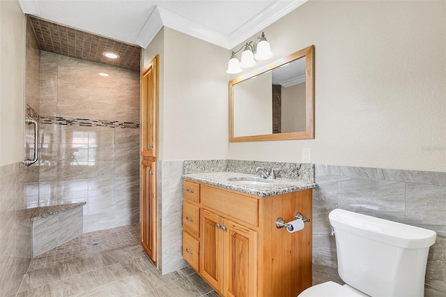 bathroom featuring toilet, tile walls, vanity, tiled shower, and ornamental molding