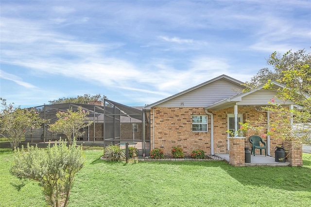 view of front of home featuring a front yard, glass enclosure, and a patio area