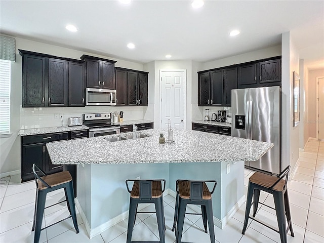 kitchen featuring a kitchen island with sink, appliances with stainless steel finishes, a breakfast bar area, and a sink