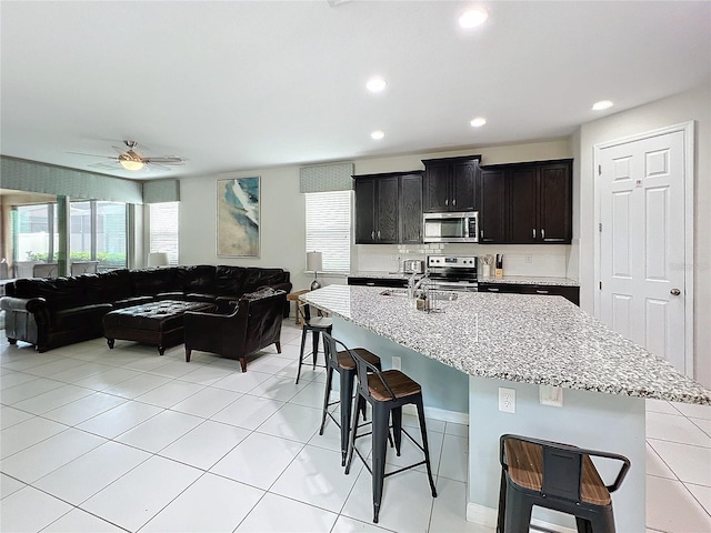 kitchen with a kitchen bar, a wealth of natural light, open floor plan, and appliances with stainless steel finishes