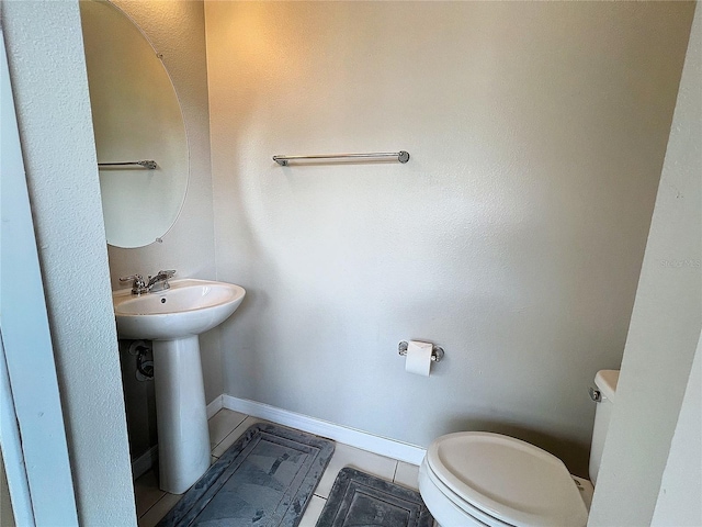 half bathroom featuring toilet, baseboards, and a sink