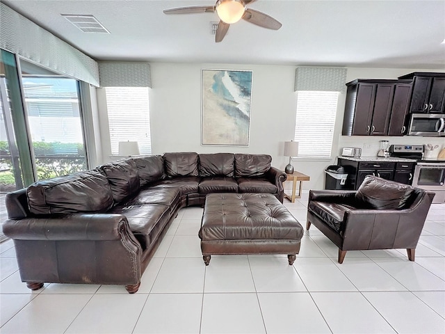 living area featuring light tile patterned flooring, visible vents, plenty of natural light, and ceiling fan