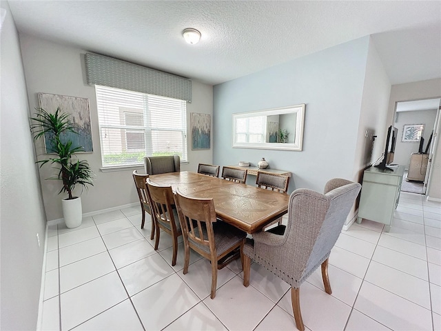 dining space with light tile patterned floors, baseboards, and a textured ceiling