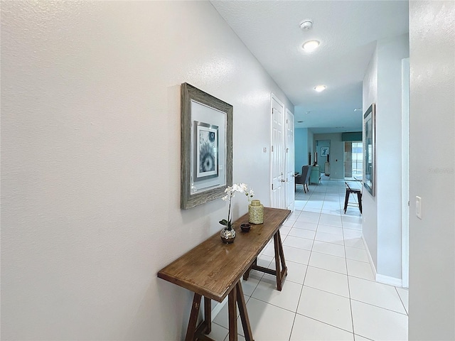 corridor featuring light tile patterned floors and baseboards