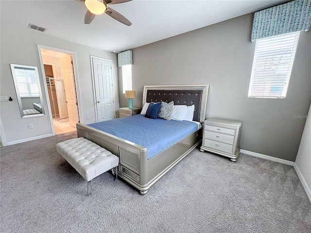 carpeted bedroom featuring visible vents, baseboards, ensuite bath, and a ceiling fan