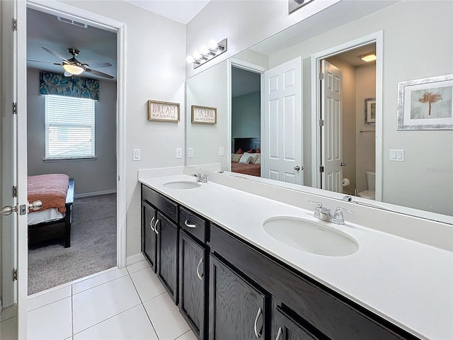 ensuite bathroom featuring tile patterned flooring, connected bathroom, toilet, and a sink