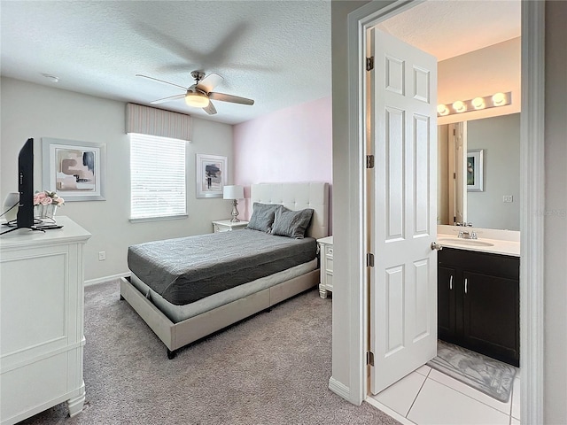 bedroom featuring a ceiling fan, a sink, a textured ceiling, light carpet, and connected bathroom