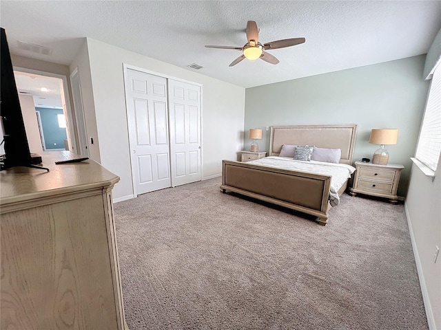 bedroom with carpet, baseboards, visible vents, a closet, and a textured ceiling