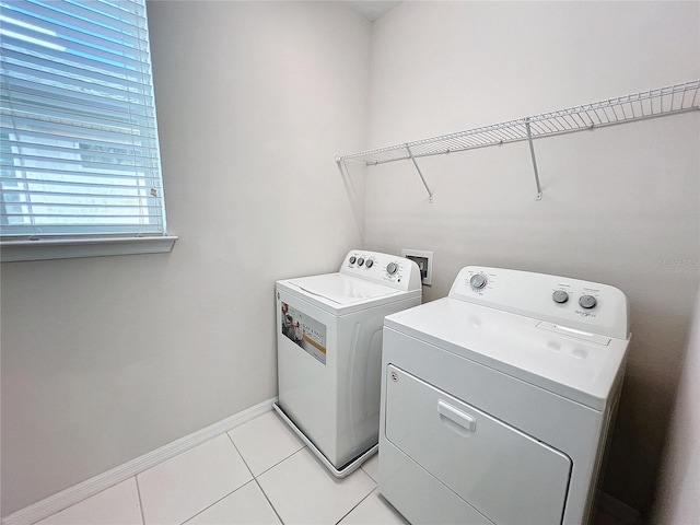 washroom with laundry area, light tile patterned flooring, baseboards, and washing machine and clothes dryer