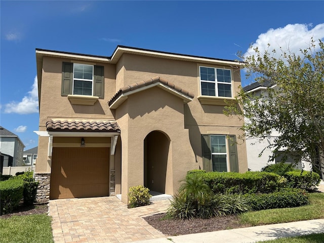 view of front of home featuring stucco siding, a tiled roof, decorative driveway, and a garage