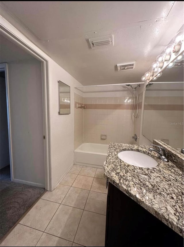 bathroom featuring tiled shower / bath, vanity, a textured ceiling, and tile patterned flooring