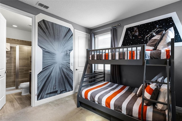 carpeted bedroom with a textured ceiling and ensuite bath