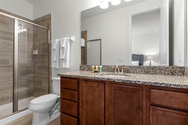 bathroom featuring toilet, a shower with door, and vanity