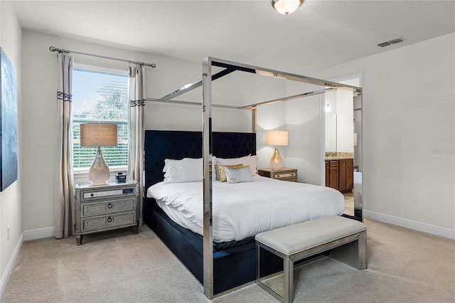 bedroom featuring ensuite bathroom and light carpet