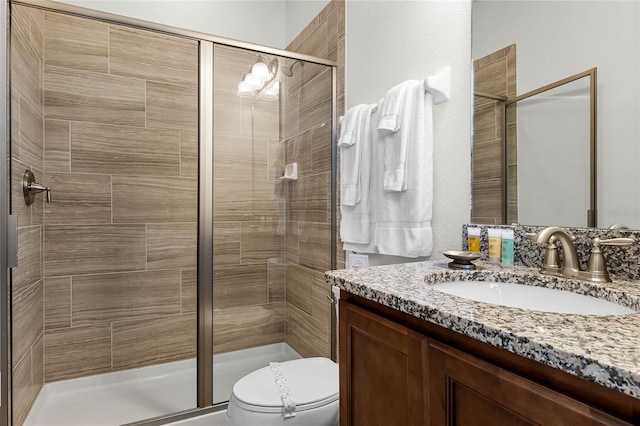 bathroom with a shower with door, vanity, and toilet