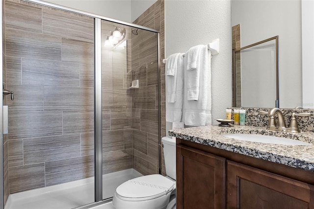 bathroom with toilet, a shower with door, and vanity