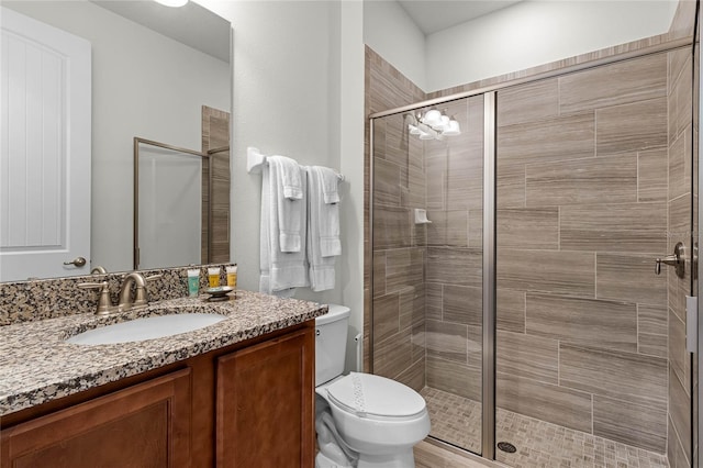 bathroom featuring walk in shower, toilet, and vanity