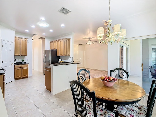 dining area featuring light tile patterned flooring, ceiling fan with notable chandelier, and sink