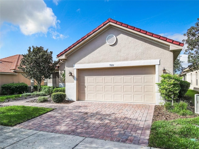 mediterranean / spanish-style home featuring central air condition unit and a garage