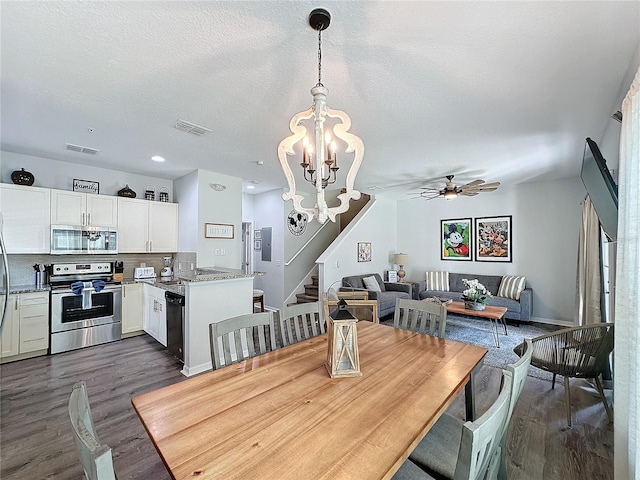 dining space with dark wood-type flooring, ceiling fan with notable chandelier, and a textured ceiling