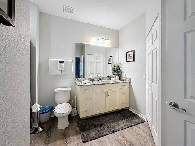 bathroom with vanity, toilet, and wood-type flooring