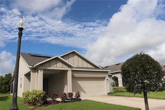 view of front of house featuring solar panels, a front yard, and a garage