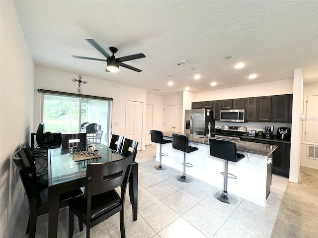 tiled dining room with a textured ceiling and ceiling fan