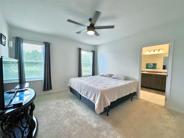 carpeted bedroom with ensuite bath, a textured ceiling, sink, and ceiling fan