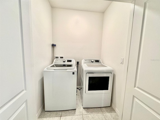 clothes washing area with washing machine and dryer and light tile patterned floors