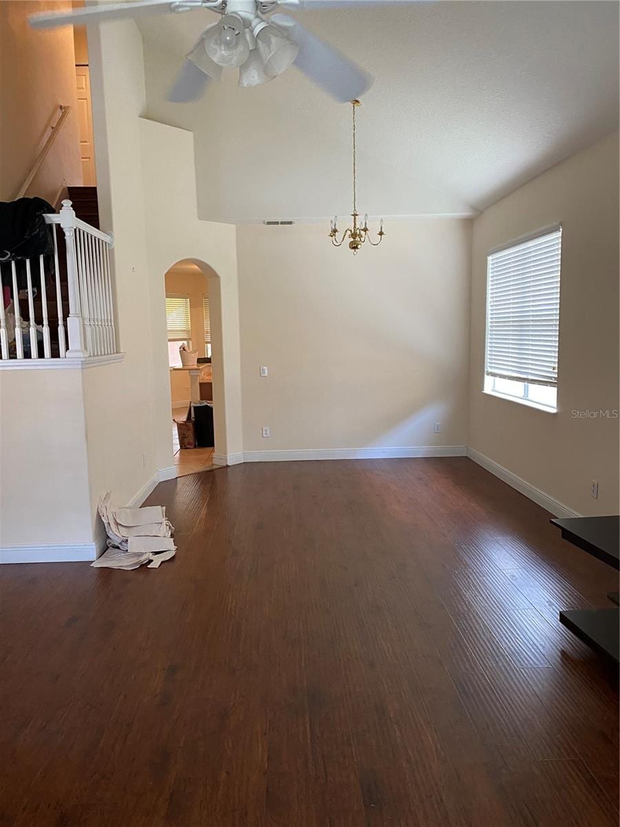 unfurnished living room featuring dark wood-type flooring and ceiling fan with notable chandelier