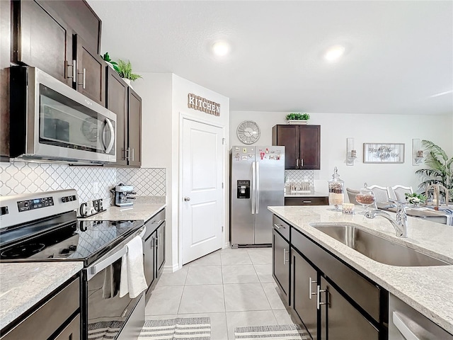 kitchen featuring sink, backsplash, stainless steel appliances, dark brown cabinetry, and light tile patterned floors