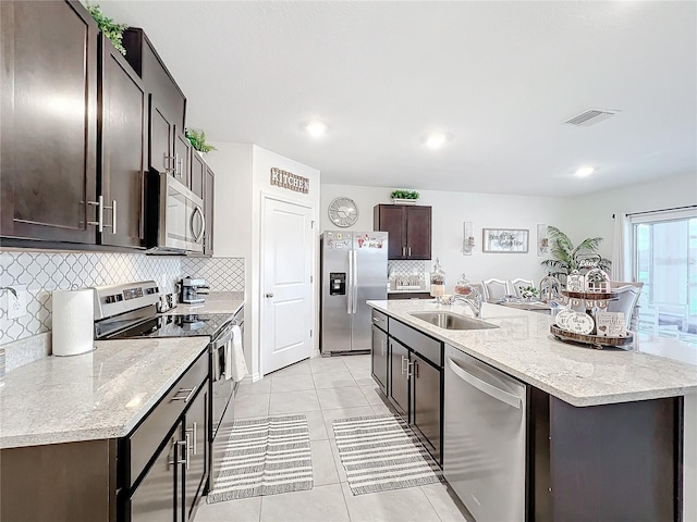 kitchen featuring light tile patterned flooring, appliances with stainless steel finishes, sink, and a center island with sink