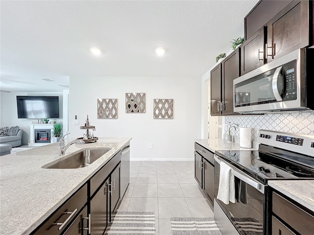 kitchen featuring decorative backsplash, sink, light tile patterned flooring, dark brown cabinetry, and appliances with stainless steel finishes