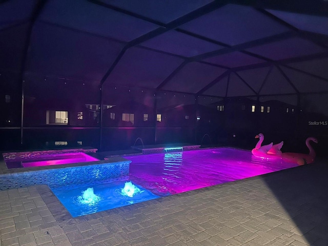 view of swimming pool with glass enclosure, a patio area, and a pool with connected hot tub