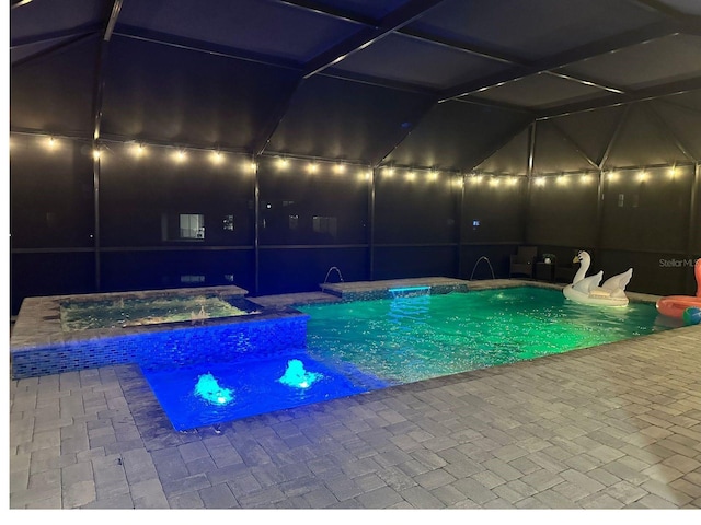 view of swimming pool featuring an in ground hot tub, pool water feature, a patio, and a lanai