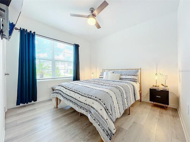 bedroom with a ceiling fan, baseboards, and light wood finished floors